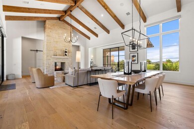 Dining room with high vaulted ceiling, a chandelier, a barn door, a fireplace, and light wood-style floors