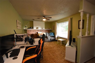 Carpeted living room featuring a textured ceiling, ceiling fan, and a fireplace