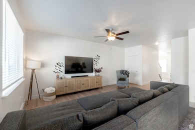 Living room featuring light wood-style floors, plenty of natural light, and ceiling fan