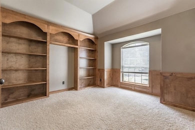 Unfurnished bedroom with wainscoting, lofted ceiling, and carpet floors