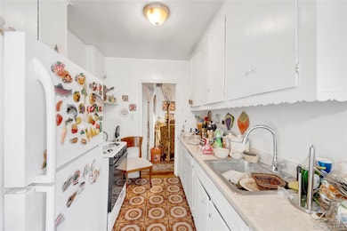 Kitchen featuring white appliances, light countertops, white cabinetry, and light floors