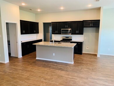 Kitchen featuring light stone counters, sink, a kitchen island with sink, light hardwood / wood-style flooring, and appliances with stainless steel finishes