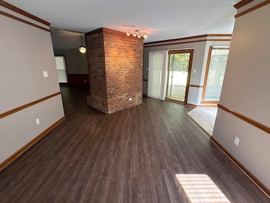 Unfurnished room with crown molding, dark wood-style flooring, a textured ceiling, and brick wall