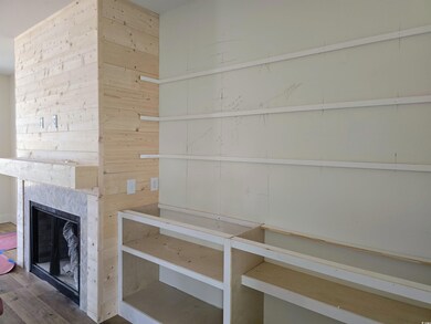 Unfurnished living room with wood finished floors, a premium fireplace, and wooden walls