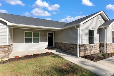 Property entrance with stone siding, roof with shingles, a yard, and a porch