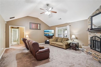 Living area featuring carpet, ceiling fan, a fireplace, and lofted ceiling