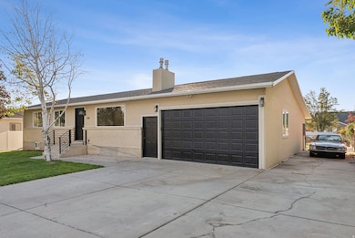 Single story home with concrete driveway, a chimney, a front yard, and stucco siding