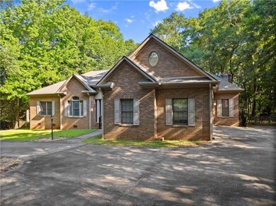 View of front of home featuring brick siding, asphalt driveway, and a chimney