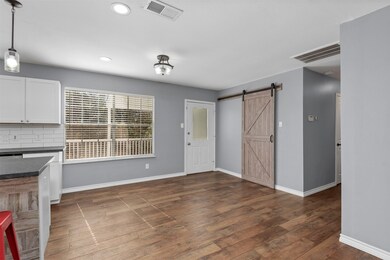 The breakfast/dining area is nearby with large windows letting natural light in. Nearby with a barn door closure is the laundry room with pantry shelves.