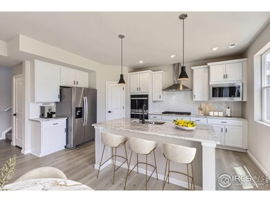 GOURMET KITCHEN WITH DOUBLE OVENS, GAS COOKTOP RANGE, HOOD VENT, MICROWAVE, AND REFRIGERATOR