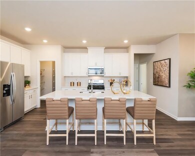 Kitchen with stainless steel refrigerator with ice dispenser, a kitchen bar, white cabinets, a kitchen island with sink, and recessed lighting