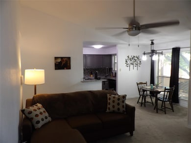 Living area with ceiling fan, light colored carpet