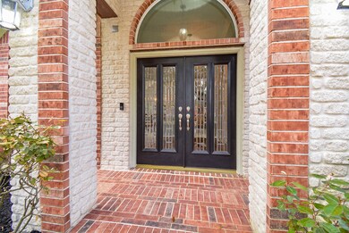 Regal defines this gorgeous main entrance. The exquisite brick foundation hosts double, glass-etched doors, which sit under the arched, clear paneled window above. The recessed, covered entrance ensures greater privacy, shelter from the elements and is roomy enough for home deliveries. Lovely!