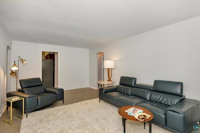 Carpeted living room featuring arched walkways and baseboards