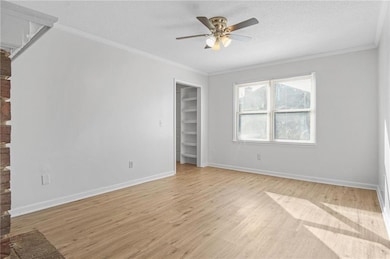 Unfurnished room with a ceiling fan, crown molding, light wood-style floors, and a textured ceiling