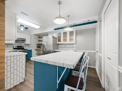 Kitchen with tasteful backsplash, stainless steel appliances, wood finished floors, and white cabinets
