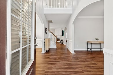 Entrance foyer featuring arched walkways, stairs, wood finished floors, and crown molding