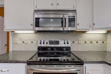kitchen with white cabinetry, backsplash, and stainless steel appliances