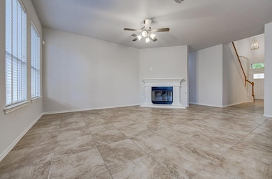 Unfurnished living room featuring a glass covered fireplace and a ceiling fan