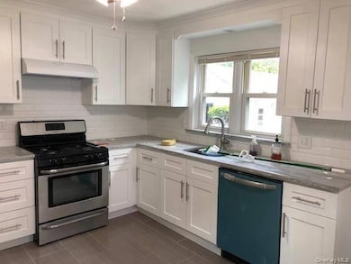 Kitchen with gas range, white cabinets, dishwasher, decorative backsplash, and under cabinet range hood