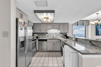 Kitchen with dark stone countertops, gray cabinetry, appliances with stainless steel finishes, decorative backsplash, and a textured ceiling