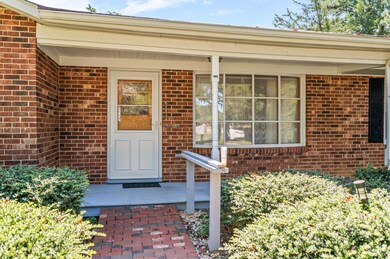 Front porch with red brick siding, covered entry, picture window, and brick walkway. - 5292 Java Rd, Java, VA 24565