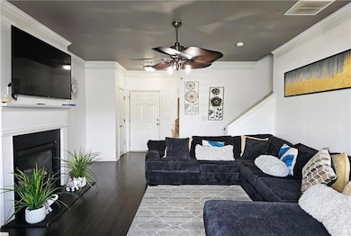 Living room with a ceiling fan, wood finished floors, ornamental molding, a glass covered fireplace, and recessed lighting