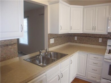 Kitchen. Glass tile backsplash with double sink and opening to dining room.