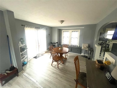 Dining space with arched walkways, light wood-style flooring, healthy amount of natural light, and a textured ceiling