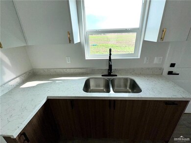Kitchen featuring light stone countertops, sink, and dark brown cabinetry