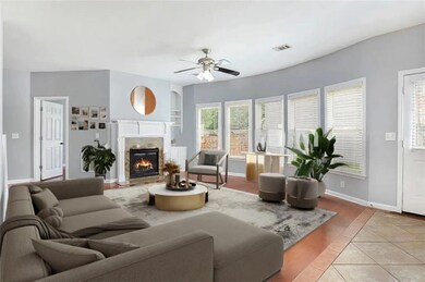 Living room with a glass covered fireplace, ceiling fan, and light tile patterned floors