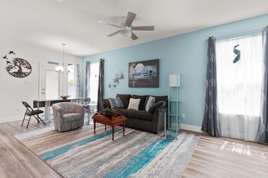 Living room with wood finished floors, a chandelier, and ceiling fan