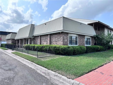View of property exterior with brick siding, fence, a yard, and metal roof