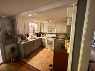 Kitchen featuring electric range oven, white microwave, wood finished floors, ornamental molding, and plenty of natural light