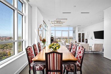 An ET2 Traverse LED light fixture adds a modern touch to the dining area, which is bathed in natural light from expansive windows offering picturesque north and west views of the Houston skyline and a seamless connection to the open living space.