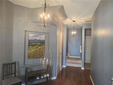 Hallway featuring an inviting chandelier, dark woo