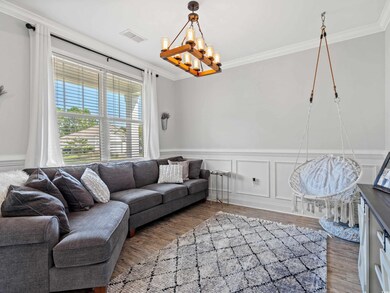 Living room with a notable chandelier, hardwood / wood-style flooring, and crown molding