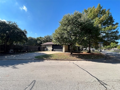 View of property hidden behind natural elements with stone siding and driveway