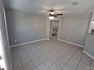 Empty room featuring light tile patterned flooring and a ceiling fan