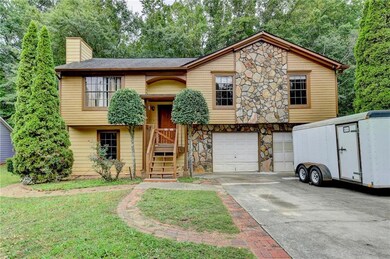 Split foyer home with a garage, stone siding, a ch