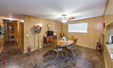 Dining room featuring baseboards, wooden walls, and a ceiling fan