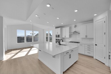 Kitchen featuring tasteful backsplash, a kitchen island with sink, white cabinetry, light wood-style flooring, and recessed lighting