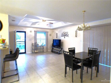 Dining area featuring baseboards, a raised ceiling, and ceiling fan with notable chandelier