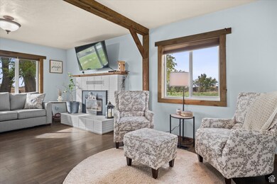 Sitting room with plenty of natural light, beam ceiling, wood finished floors, and a brick fireplace