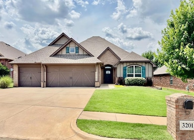 View of front of home featuring a garage, driveway, roof with shingles, brick siding, and a front yard