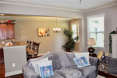 Living area featuring ornamental molding, dark wood-style floors, and a chandelier