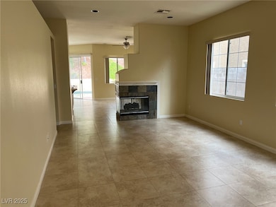 Unfurnished living room featuring a fireplace, a ceiling fan, and light tile patterned floors