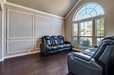 Living area featuring lofted ceiling, ornamental molding, dark wood-type flooring, and a decorative wall