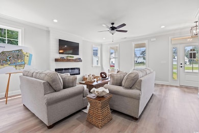 Living room with ornamental molding, recessed lighting, a glass covered fireplace, light wood-style floors, and a ceiling fan