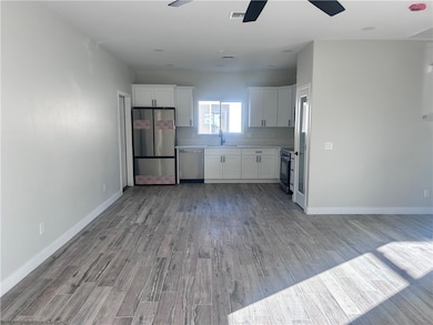 Kitchen featuring white cabinets, stainless steel appliances, light countertops, dark wood-type flooring, and ceiling fan